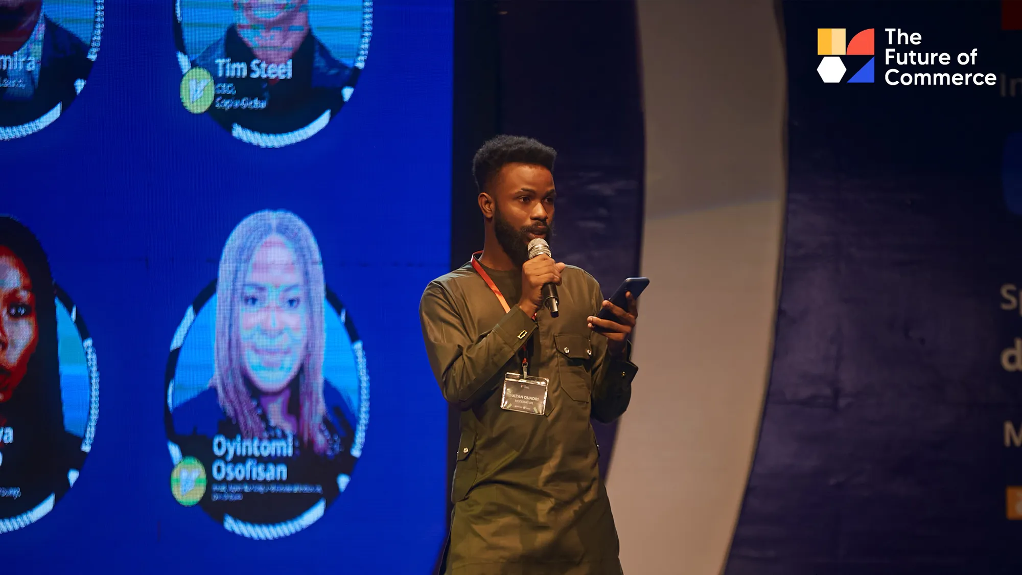 A speaker presenting on stage at The Future of Commerce in front of branded event screens.